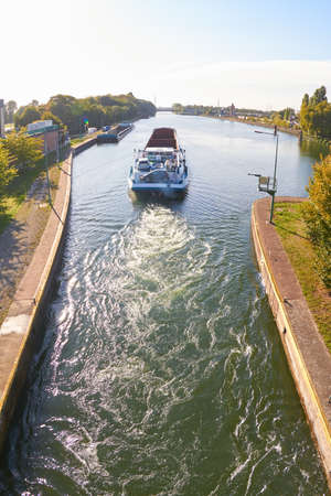 A barge is sailing on a canal in bright sunshine.