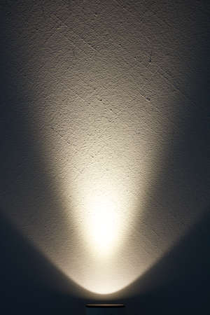 A bright lamp produces a light beam on a wall.の写真素材