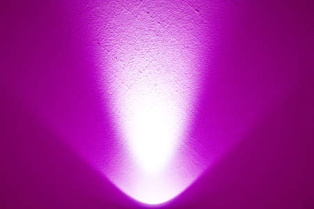A bright lamp produces a light beam on a wall.の写真素材