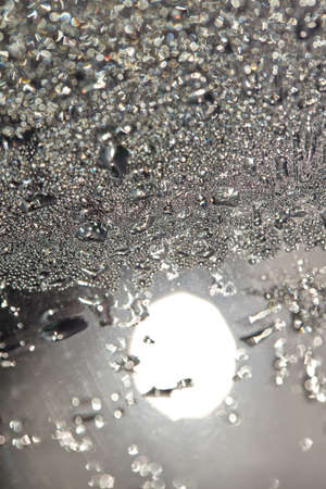 Small dewdrops on a glass pane in the sun.