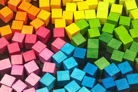 Colorful wooden dice lie on a black metal plate.の写真素材