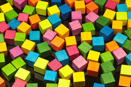 Colorful wooden dice lie on a black metal plate.の写真素材