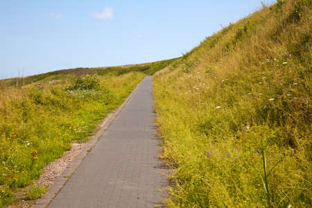 In the sunshine, a path leads up to a slag heap.