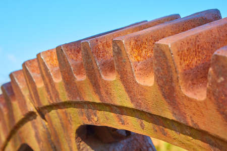 An old, rusty gear against a blue sky.の写真素材