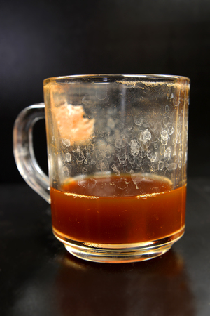 Dirty glass filled with coffee on a dark backgroundの写真素材