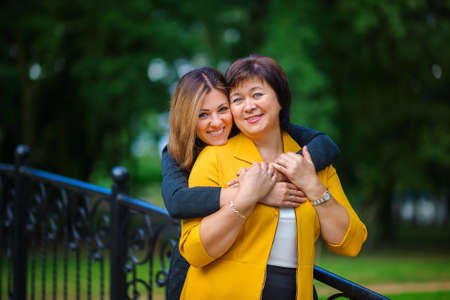 the adult daughter embraces the elderly mother and together smile