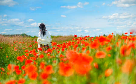 the beautiful girl with thoughtful a look walks in the poppy fieldの写真素材