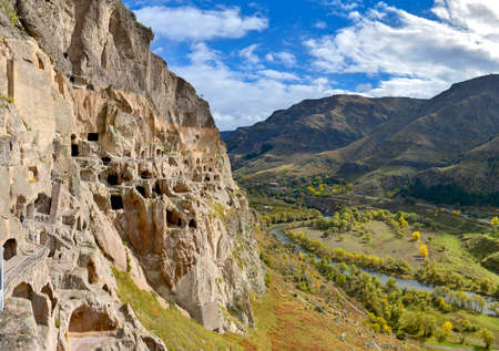 ancient cave monastery in the mountains of Georgia, premises of the monastery are cut down directly in the rock, a beautiful view from the mountain on the valleyの写真素材