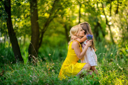 girl the outdoors, small bouquet of flowers, manifestation of tender feelings and care embrace mother, smile each other, a close-knit family, the relations of children and parentsの写真素材