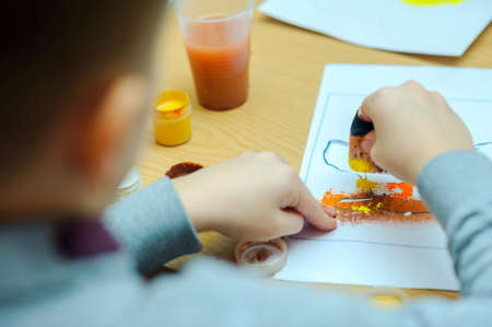 ?hild, Boy of school age, does hand-made articles on a school table,accurately decorates with a...