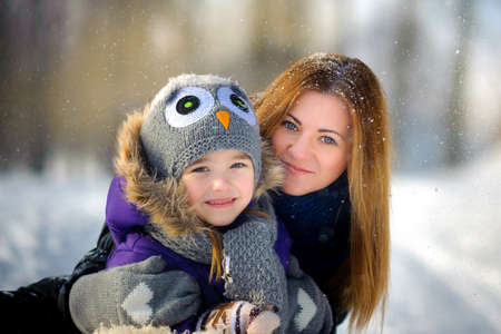 mother embraces the daughter and together smile for the camera, beautiful snow falls, a close-knit...