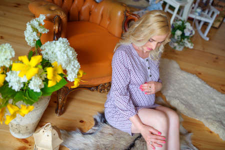 happy mother waiting for the child's birth, sits on a floor pensively stroke-oars on a tummy and smiles, happy pregnancy, motherhoodの写真素材