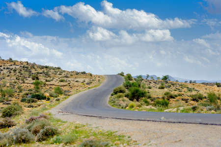 road in desert mountains winding on slopes, the bright blue sky on the horizonの写真素材