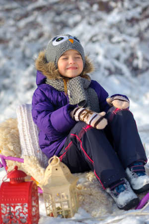 girl with the sledge plays on a snow glade, joyful holiday mood on the eve of Christmas, family...