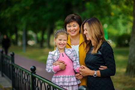 happy family together with the grandmother poses in the park, all together look in the camera and smileの写真素材