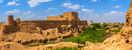 old clay fortress at hill top, over the city of Meybod in Iran, the fortress and the city from clay of orange color, on the sky float white cloudsのeditorial素材