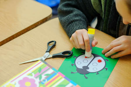 ?hild, Boy of school age, does hand-made articles on a school table, a God's cow on the green sheet of paperの写真素材