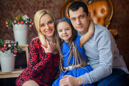 family of three people poses indoors, amicably embrace and pose on the camera, strong family bonds, a close-knit familyの写真素材