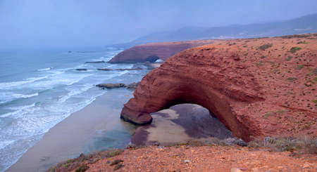 Natural arches on the beach of a legzir in Morokko, Two huge arches from red breed in a rebag with a stone, on the bank of the Atlantic Oceanの写真素材