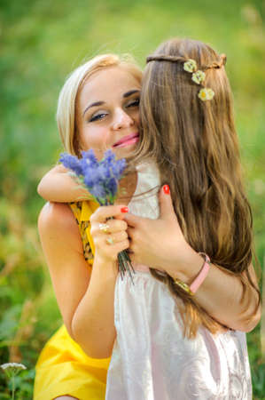 girl the outdoors, small bouquet of flowers, manifestation of tender feelings and care embrace mother, smile each other, a close-knit family, the relations of children and parentsの写真素材