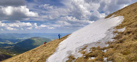 Group of the people ascending on the mountain, the sky in clouds, the beautiful view opening on the valley with top, a unification with the nature and serenityの写真素材