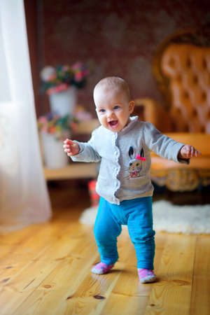 little girl takes the first steps, in an interior of studio, on a background elder sister