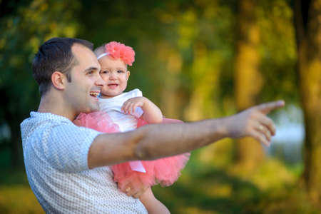 father with the beloved little daughter, walk in the beautiful park, smile and admire a declineの写真素材
