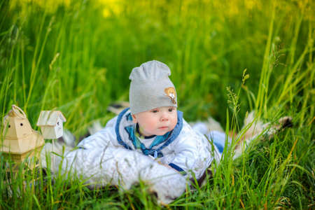 newborn boy in the beautiful park outdoors, lies on a pillow and with astonishment looks aroundの写真素材