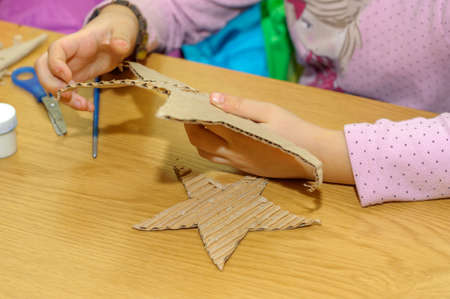 Children at a lesson of the fine arts, make gifts for a holiday of Christmas and new year. Cut out and do garlands of sheets of a cardboard. Preparation for a holiday.の写真素材