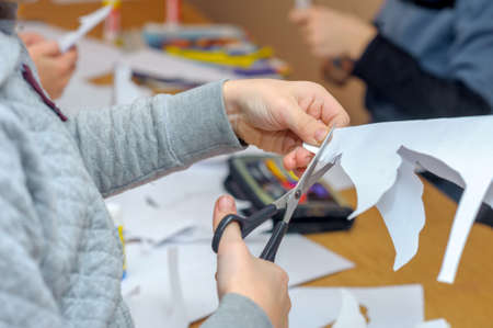 Children at a lesson of the fine arts, make gifts for a holiday of Christmas and new year. Cut out hand-made articles in the form of angels from sheets of paper. Preparation for a holiday.の写真素材