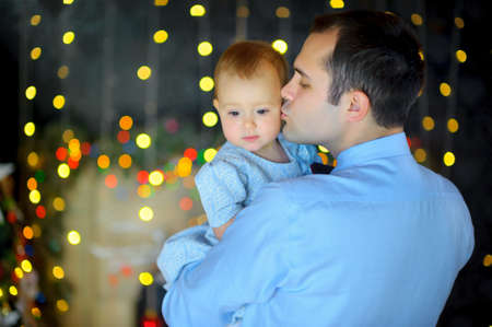 happy father stick on hands small to the daughter, strong embraces and kisses. Bright festive fires on a background. Waiting for a holiday.の写真素材
