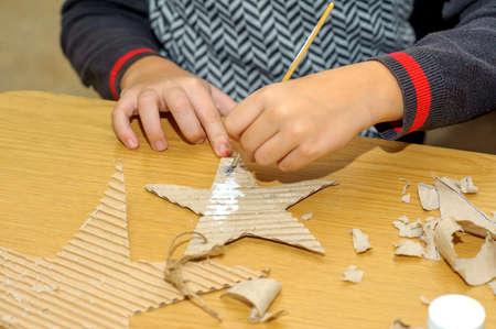 Children at a lesson of the fine arts, make gifts for a holiday of Christmas and new year. Cut out and do garlands of sheets of a cardboard. Preparation for a holiday.の写真素材