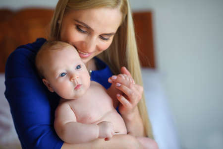 happy mother holds on hands of the newborn baby, smiles and presses to a breastの写真素材