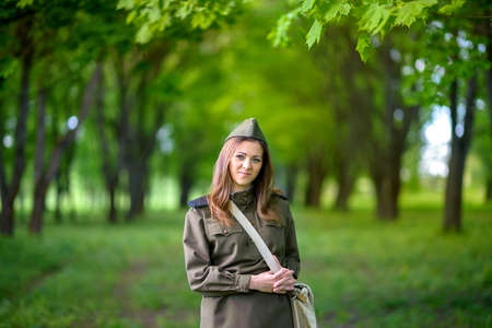 woman in the uniform of the military poses in the beautiful spring parkの写真素材