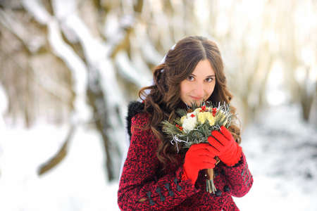 The beautiful bride with a bouquet, in the snow old park, gently holds a bouquet and smilesの写真素材