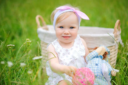 cheerful girl plays sitting on a grass in the beautiful park, looks in the camera and smilesの写真素材