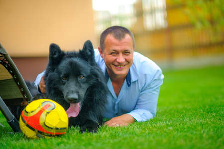 man with the favourite dog lies on a grass and smilesの写真素材