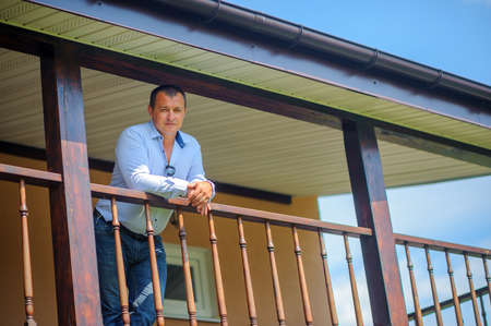 confident man costs on a terrace of the houseの写真素材