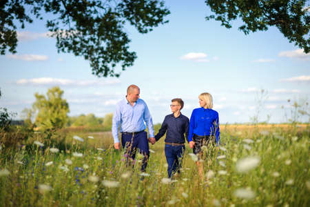 happy family walks in the evening in the field among wild flowersの写真素材