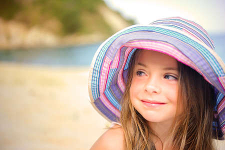 happy girl in a beach hat sits on sand near the seaの写真素材