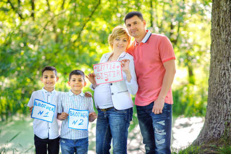 big happy family in anticipation of the birth of daughter, walking in the park at sunsetの写真素材