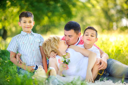 Happy family rest on nature in park, sit on the grass hugging and having funの写真素材