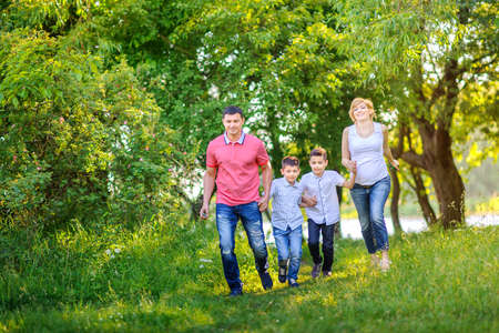 Happy family rest on the nature in the park, held together by the hands and having funの写真素材