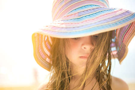 little girl in a beach hat walks on the seashoreの写真素材
