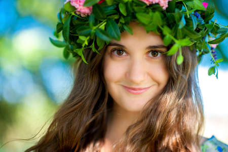 happy smiling girl in the park with a branch of flowers on the headの写真素材