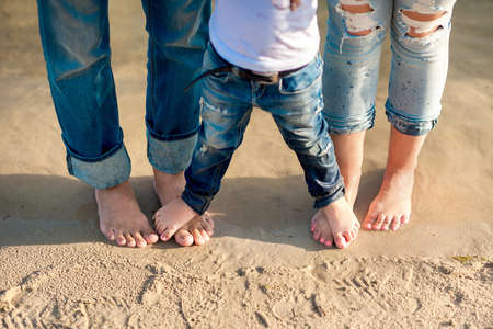 girl is standing barefoot at the feet of her parents