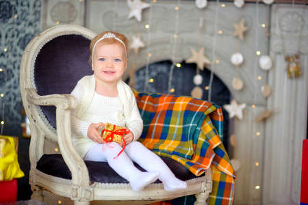 happy girl with a gift in hands, sits on an armchair and smilesの写真素材