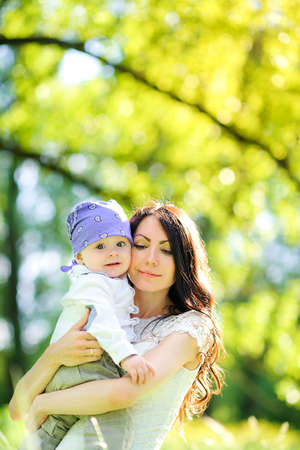 happy mother in her young son in the park at sunset, hugs and clings to her chestの写真素材
