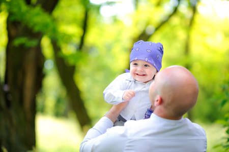 Dad plays with his beloved son in the evening park, kid joyfully smilesの写真素材
