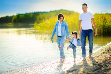 happy family walks on the nature near the lake, go for a ride on the water and splashの写真素材